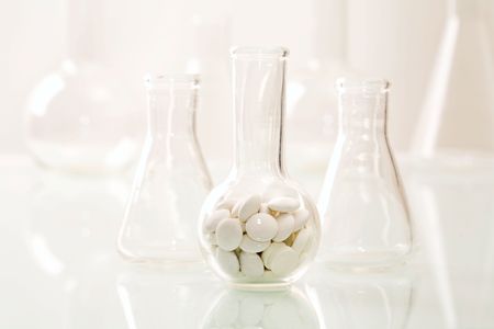 Image of flask with tablets on the background of different glass jars
