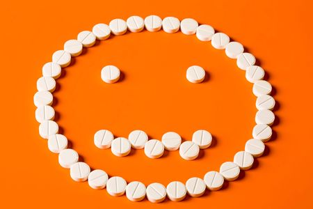Image of face made up out of white tablets on the orange backgroundの写真素材