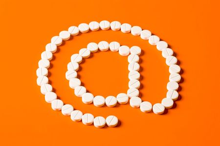 Sign-@ made up out of white tablets on the orange backgroundの写真素材