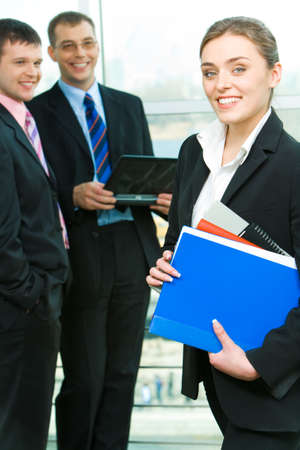 Portrait of business woman holding the folders on the background of businessmen