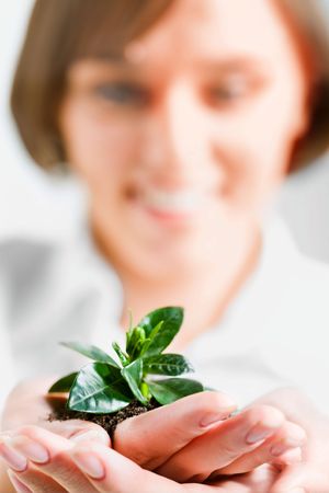 Pretty woman is holding the sprout in her armの写真素材