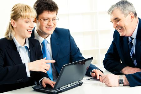 Photo of successful people in front of laptop while woman pointing at its monitor with astonishmentの写真素材