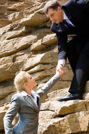 Image of businessman standing on the mount and holding blond woman by handの写真素材