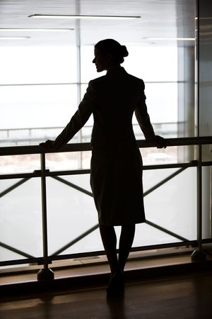 Silhouette of business ladys back standing on the balcony and touching its railingの写真素材