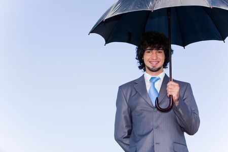 Image of successful businessman under his umbrella of background of skyの写真素材