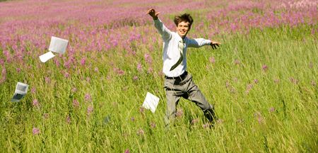 Photo of happy businessman running upon green field on windy day in summerの写真素材
