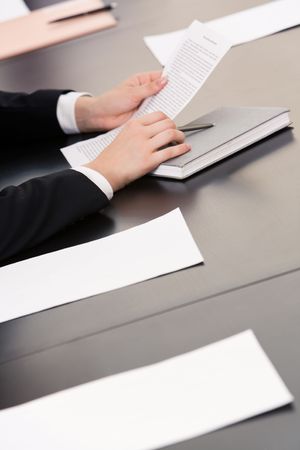 Image of human hands holding pen and documents with notebook, papers near by on the table   の写真素材