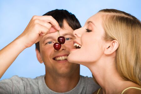 Portrait of young woman looking at cherry in manÂs handの写真素材