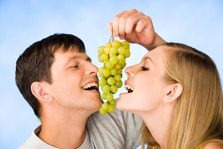 Portrait of man and young woman eating bunch of grapes の写真素材
