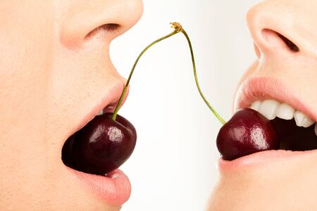 Image of succulent cherries in human mouths on a white background の写真素材