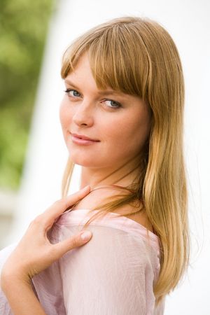 Portrait of fashionable woman touching her shoulder and looking at camera from asideの写真素材