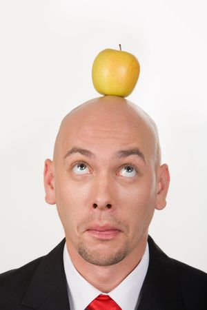 Funny businessman having apple on his head and looking at itの写真素材