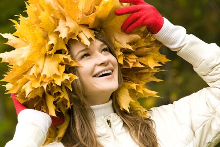 Happy girl with wreath made of yellow maple leaves on head looking upwards and laughing