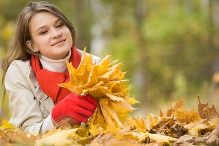 Portrait of pretty young female holding dry leaves in hand and smilingの写真素材