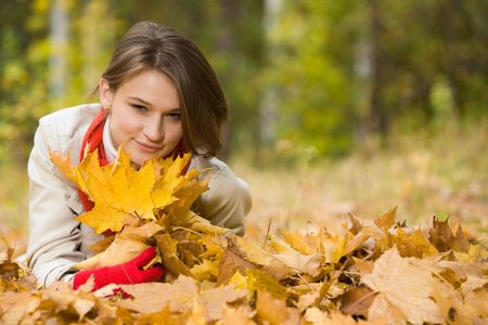 Image of cute young woman lying on autumnal land in the park の写真素材