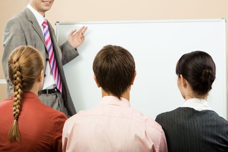 Rear view of business partners listening to lecturer and looking at whiteboardの写真素材