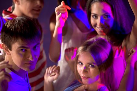 Smart teenagers looking at camera while dancing at discoの写真素材