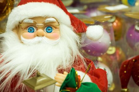 Photo of toy Santa Claus wearing eyeglasses and red fur cap in shopping mallの写真素材