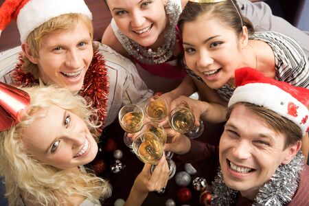 View from above of merry friends with flutes of champagne looking upwards