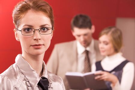 Smart businesswoman in eyeglasses looking at camera in working environmentの写真素材