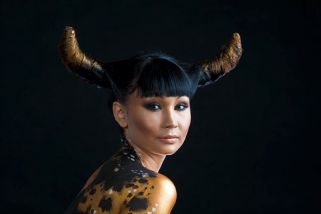 Portrait of serious woman with hairstyle in form of horns looking at camera over black backgroundの写真素材