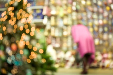 Image of blurred new year fir tree in mall with woman wearing pink coat at backgroundの写真素材