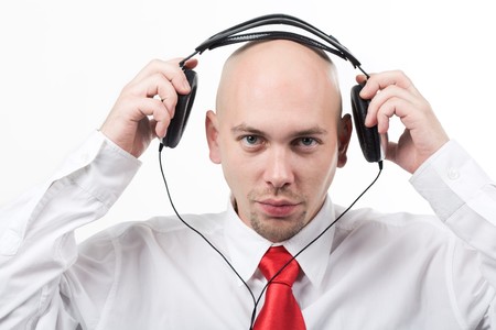 Portrait of serious male putting headphones on his head and looking at cameraの写真素材