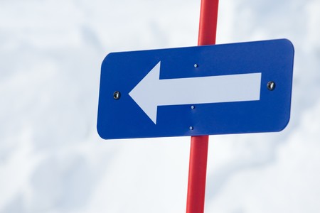 Close-up of white arrow on blue board pointing to the leftの写真素材