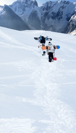 Image of two snowboarders rising to the mountain top in winterの写真素材