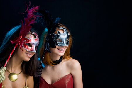 Portrait of attractive ladies holding carnival masks and looking through themの写真素材