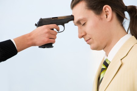 Profile of very sad businessman with gun at his forehead held by womanの写真素材