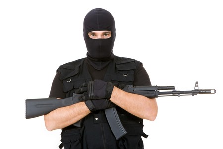 Portrait of violent killer holding firearm and looking at camera with balaclava on his head