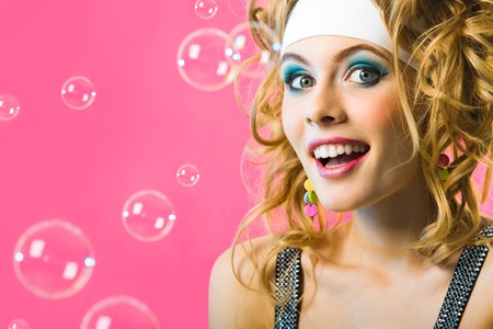 Photo of happy girl surrounded by soap bubbles on pink backgroundの写真素材