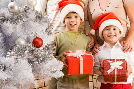 Portrait of happy siblings in Santa caps holding giftboxes in handsの写真素材