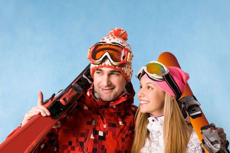 Portrait of happy couple holding skis and communicating with each otherの写真素材