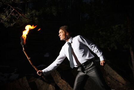 Image of brave man with burning stick in darknessの写真素材