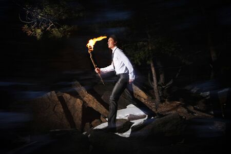 Image of brave man holding burning stick while moving in darknessの写真素材