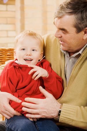Portrait of cute kid having fun with his grandfather near by