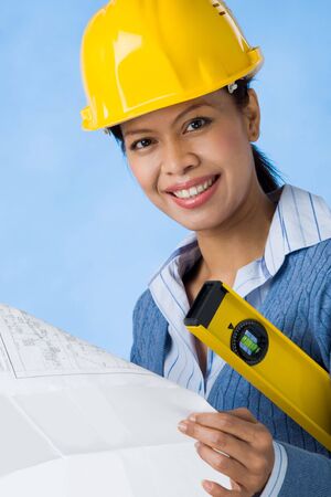 Portrait of pretty female with blueprints in hands and helmet on head smilingの写真素材