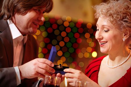 Image of beautiful woman looking into small open box before her being given by manの写真素材