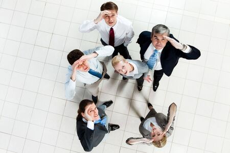 Portrait of confused business group standing on the floor and looking at camera