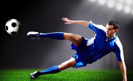 Image of soccer player doing flying kick with ball on football fieldの写真素材