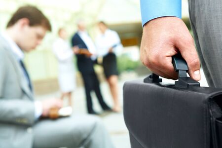Close-up of businessman hand holding briefcase in working environmentの写真素材