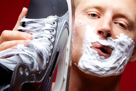 Portrait of young man with foam on face shaving with skate razor
