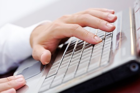 Close-up of male hand touching button of silver laptop keyboardの写真素材