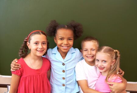 Image of clever schoolchildren standing by blackboard and looking at camera の写真素材