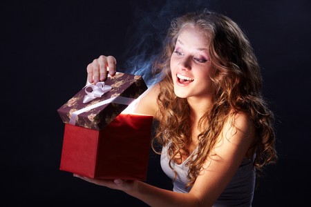 Image of pretty woman looking into gift box and wonderingの写真素材