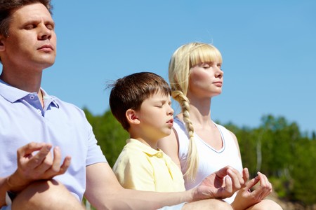 three family members meditating on summer day outdoorsの写真素材