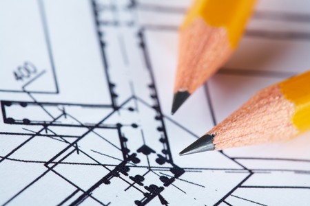 Close-up of blueprints with sketch of project on workplace and two pencilsの写真素材