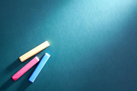 Close-up of three colorful pieces of chalk on blackboardの写真素材